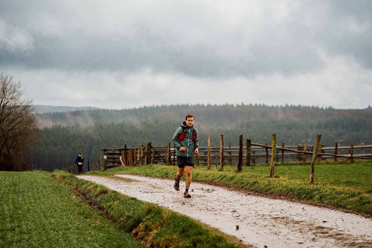 Un coureur sur un chemin de prairie, la vallée de la Haute Ardenne derrière lui