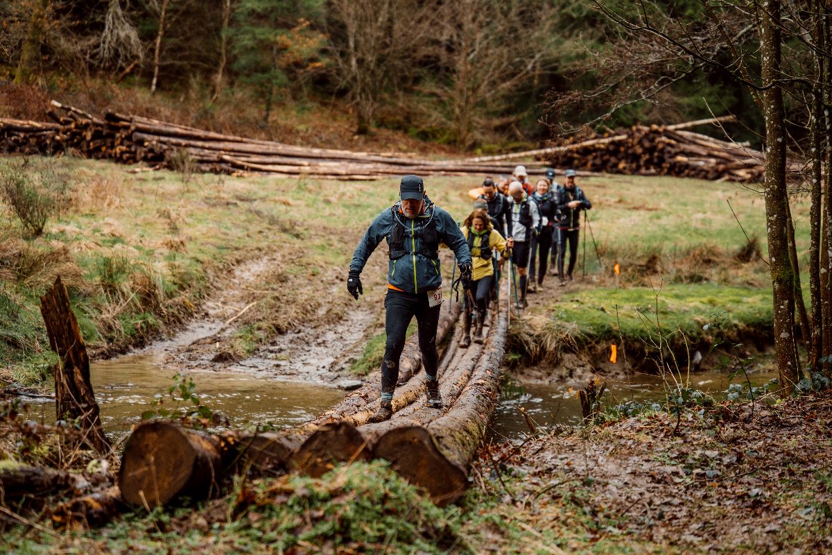 La file des coureurs sur un pont de troncs au-dessus du ruisseau